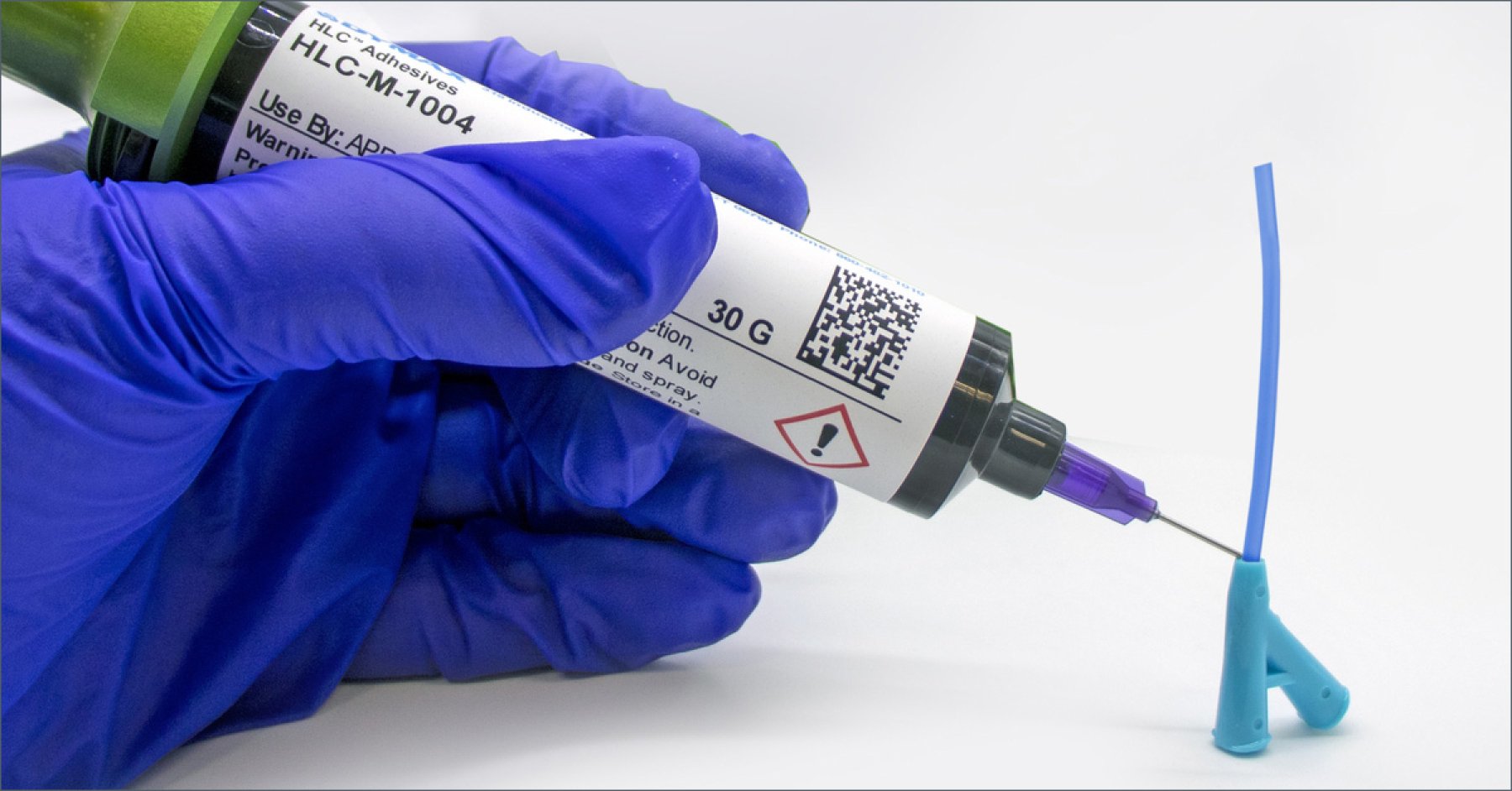 Dymax HLC-M-1004 adhesive is dispensed by hand via syringe onto opaque medical components